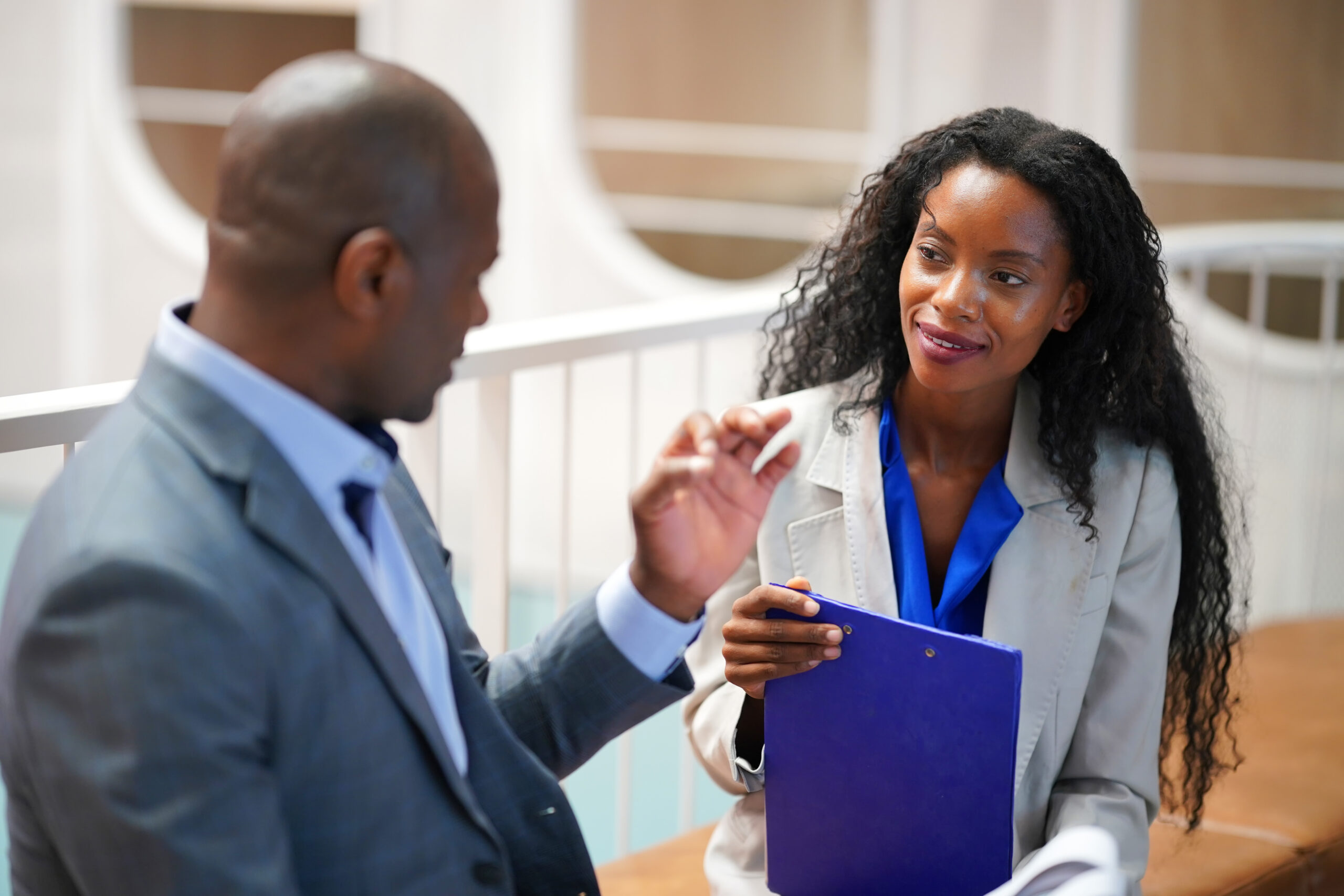 A man and a women sitting in suits talking about recovery for professionals.